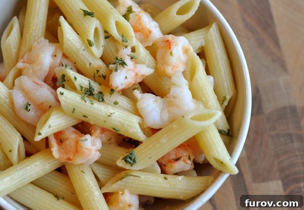 Top-down view of a vibrant butter garlic shrimp penne dish in a white bowl, ready to be enjoyed.