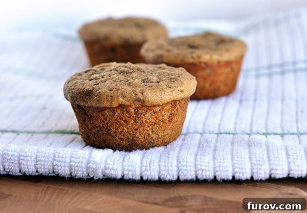 Three cooked bran muffins on a kitchen towel. 
