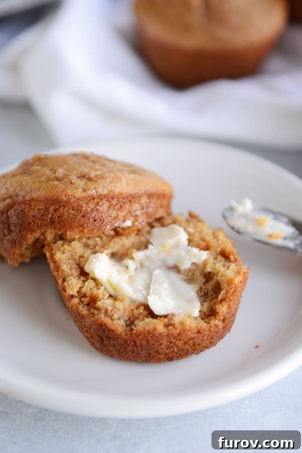 A bran muffin split in half with butter spread on it. 