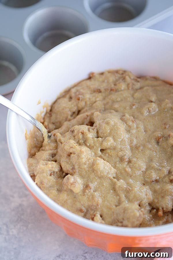 Bran muffin batter in an orange bowl with a spoon on the side. 