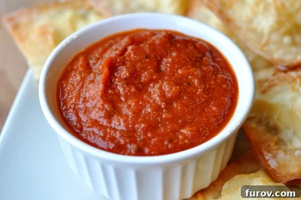 Timeless Marinara Sauce 2 A white ramekin overflowing with vibrant red marinara sauce, surrounded by golden-brown garlic bread slices, all presented on a pristine white platter. Perfect for dipping!
