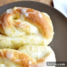 Golden Orange Swirls 12 A freshly baked orange sweet roll, generously drizzled with a vibrant orange glaze.