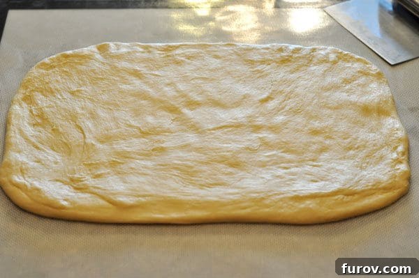 Golden Orange Swirls 5 Smooth, uncooked bread dough rolled into a perfectly even rectangle shape on a floured surface, ready for filling.