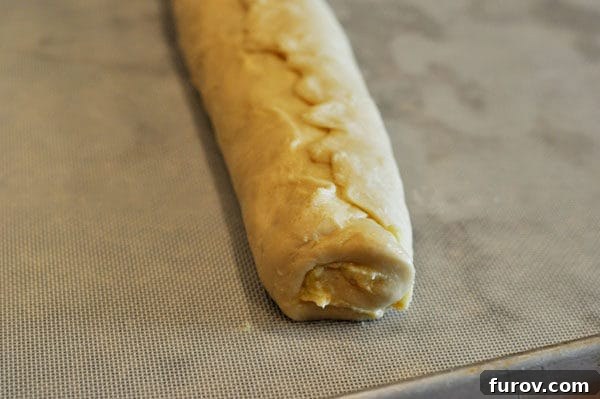 Golden Orange Swirls 7 Neatly rolled bread dough log with the seam pinched closed, resting seam-side down.