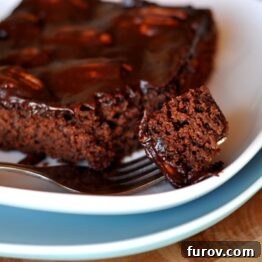 A square piece of Mississippi Mud Cake on a white plate with a fork.