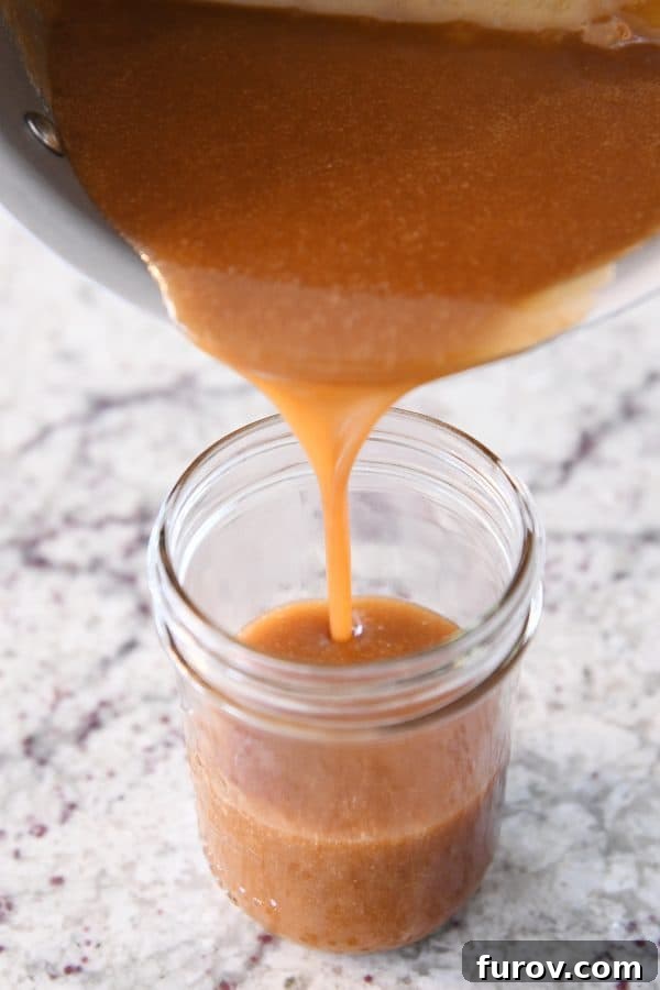 From Scratch Golden Caramel Bliss 13 Warm homemade caramel sauce being poured into a clean glass jar for storage.