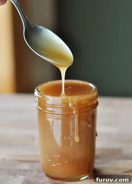 From Scratch Golden Caramel Bliss 16 A glass jar of rich caramel sauce, with a tempting drip running down its side.