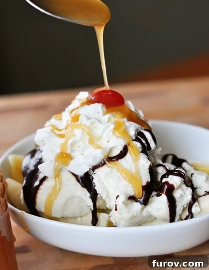 From Scratch Golden Caramel Bliss 17 A white bowl filled with vanilla ice cream, generously topped with both caramel sauce and hot fudge, and garnished with a bright red cherry.