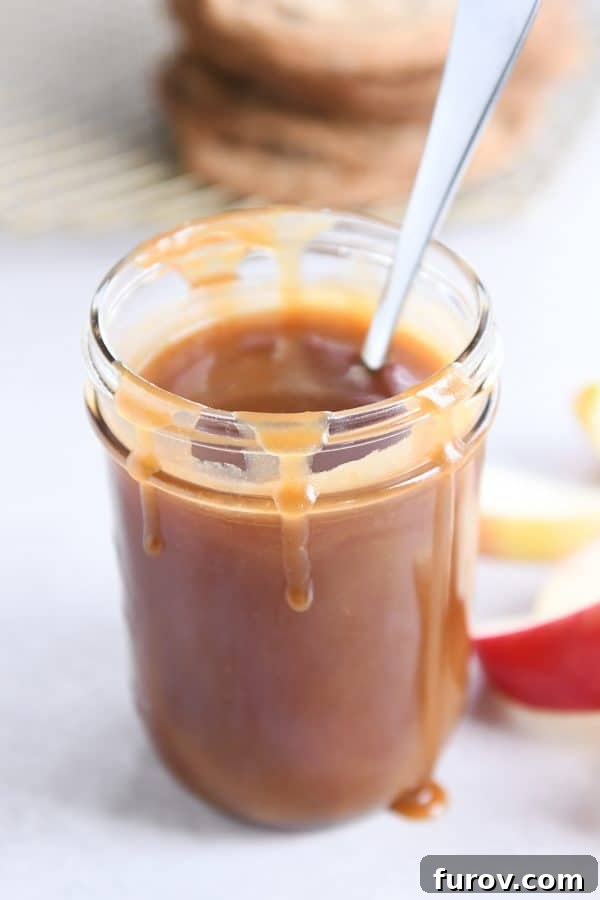 From Scratch Golden Caramel Bliss 5 Homemade caramel sauce glistening in a glass jar, with a spoon resting nearby.