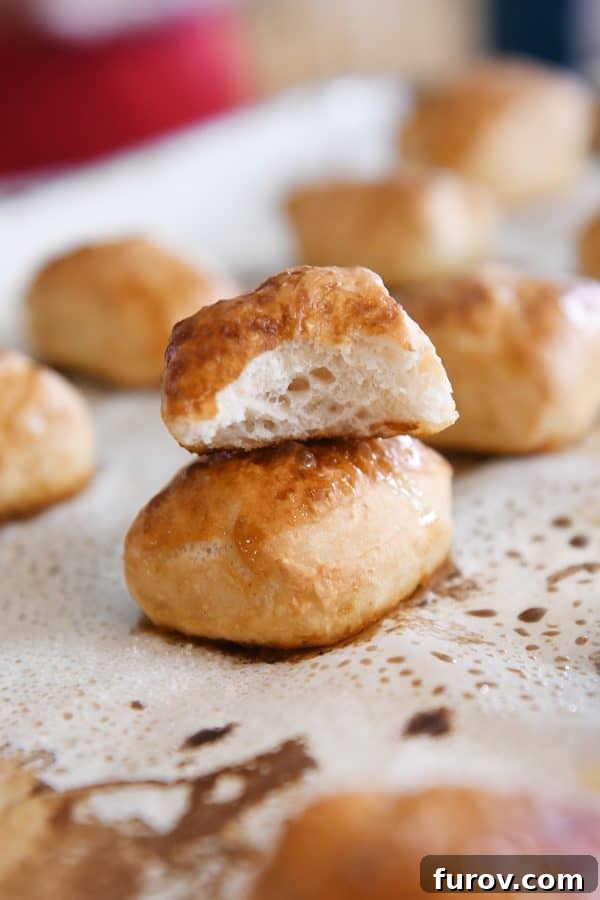 Irresistible Homemade Pretzel Bites 3 Soft pretzel bite in half on top of another pretzel bite on sheet pan.