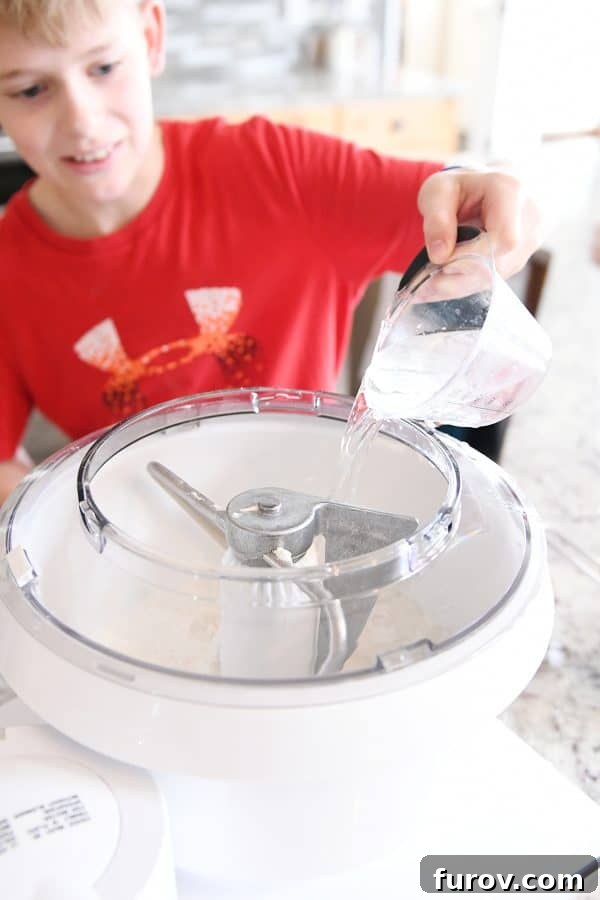Irresistible Homemade Pretzel Bites 7 Pouring water into bosch mixer for easy homemade soft pretzel bites.