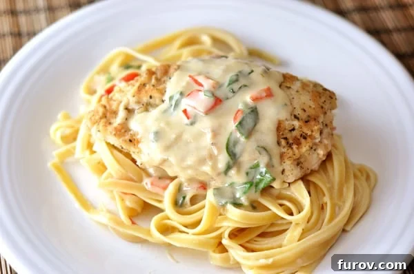 Restaurant Style Tuscan Garlic Chicken 3 Top down view of a white plate with cooked fettuccine, a breaded chicken breast, and a pepper cream sauce.