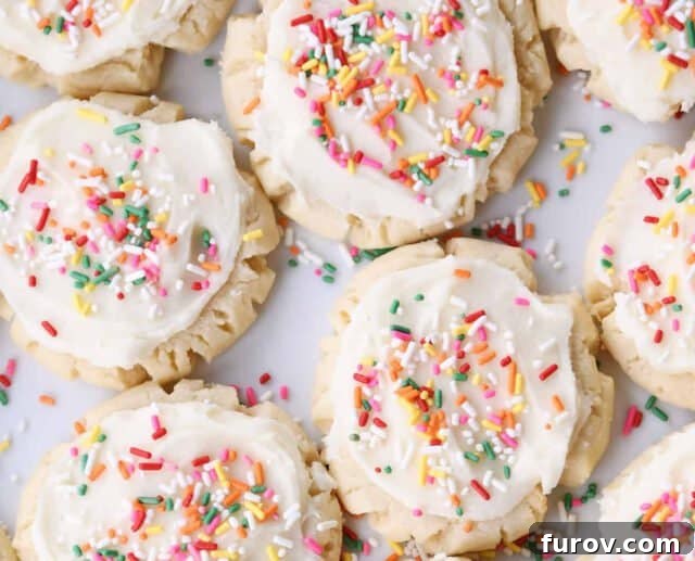 A top-down view of beautifully frosted sugar cookies, adorned with colorful sprinkles, arranged on a surface.