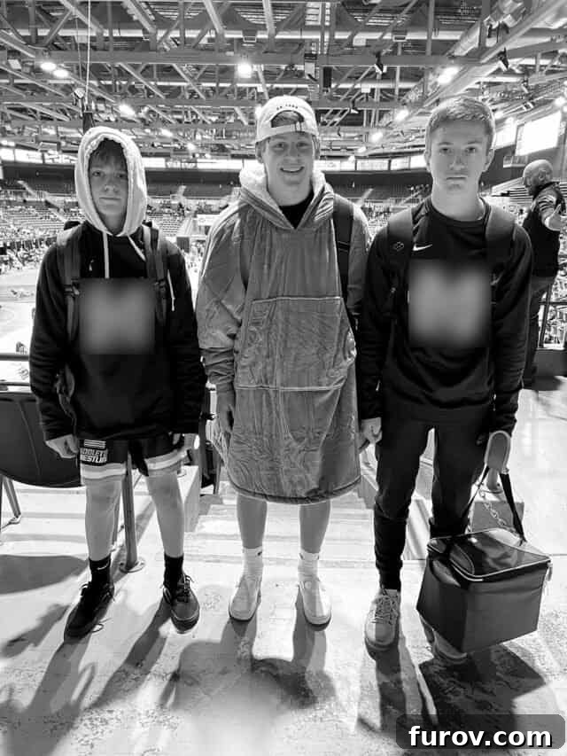 Three teenage boys, dressed in wrestling singlets, posing for a photo with serious expressions.