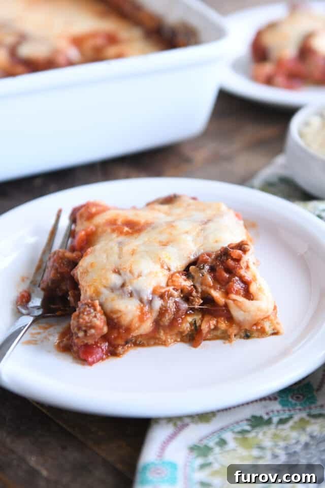 Golden Cheesy Zucchini Spaghetti Bake 2 Square of zucchini spaghetti casserole on white plate with fork.