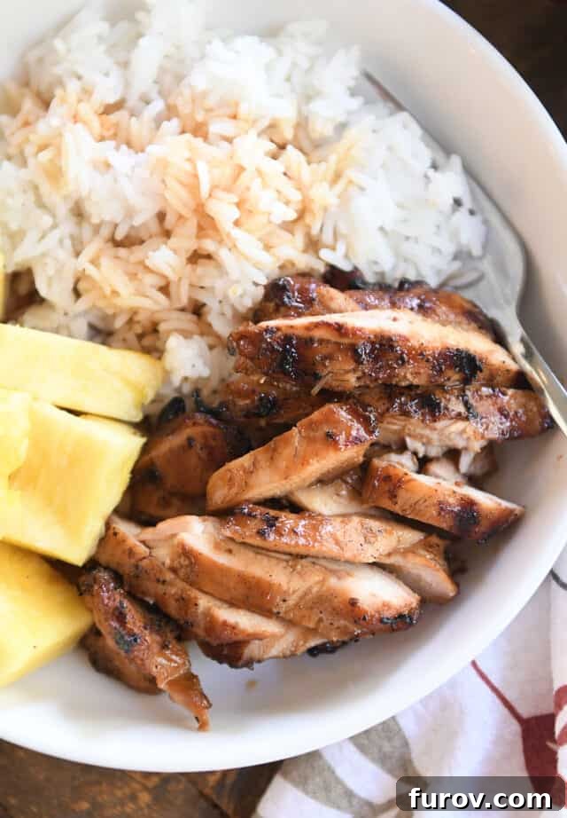 Grilled Chicken with Our Signature Teriyaki Glaze 2 Slices of grilled teriyaki chicken in white bowl with rice and pineapple.