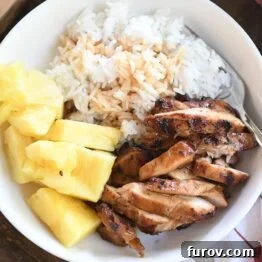 top down view of grilled teriyaki chicken in white bowl with rice and pineapple