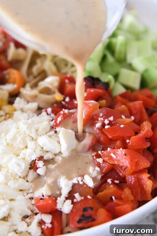 Zesty Mediterranean Pasta Salad 4 Pouring vinaigrette dressing over red peppers and feta cheese.
