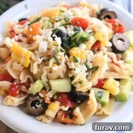 Serving of Greek pasta salad on white plate with fork to the side.