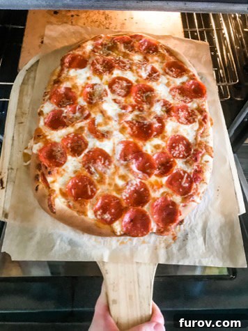 Homemade pizza on wooden pizza peel.