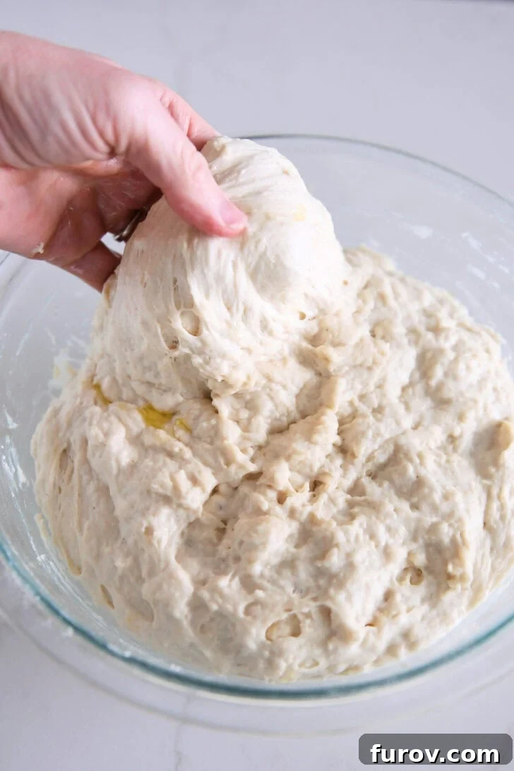Foolproof No Knead Fluffy Focaccia 14 A side view of the stretch and fold process, showing the dough being lifted and stretched.
