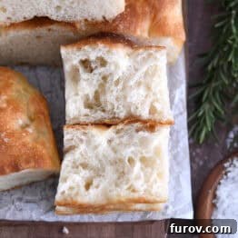 Foolproof No Knead Fluffy Focaccia 17 Two pieces of easy no-knead focaccia on white parchment paper, showing the fluffy crumb.