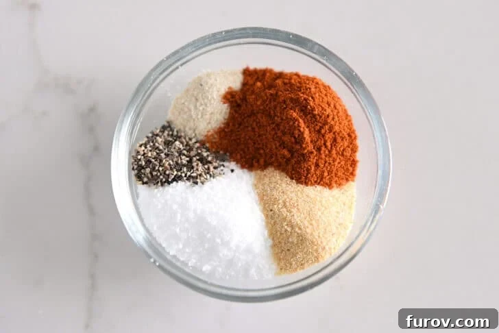 Black pepper, salt, onion powder, garlic powder, and paprika in glass bowl.