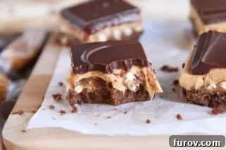 peanut butter pretzel caramel chocolate bar on piece of white parchment paper with bite taken out