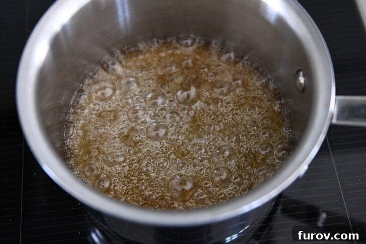 Sugar and water simmering in saucepan and turning golden brown in color.