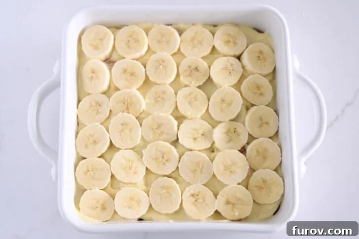 White square 8X8 baking dish with sliced bananas over the vanilla pudding.