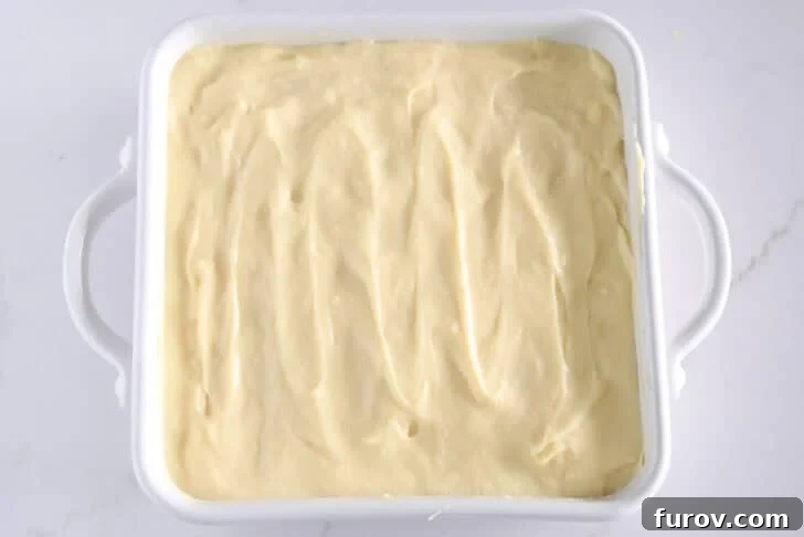 White square 8X8 baking dish with vanilla pudding on top of bananas and nilla wafers.