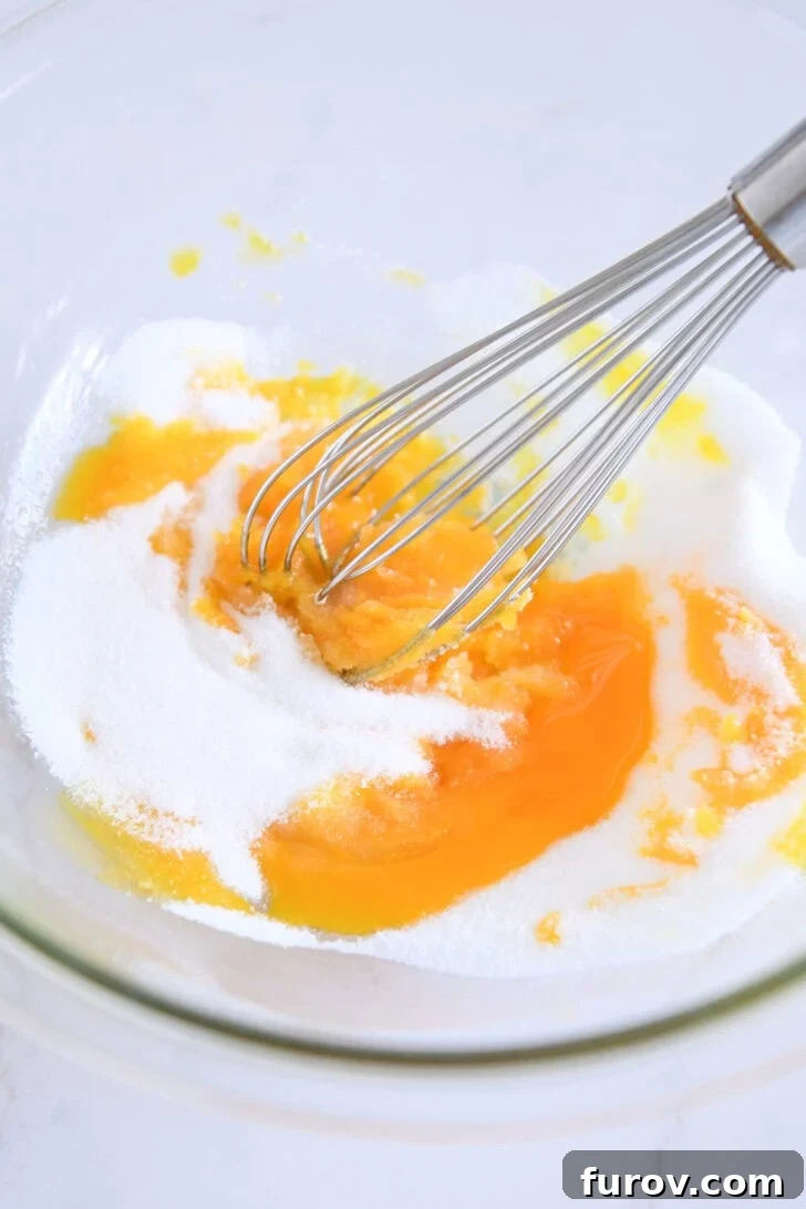 Glass bowl with egg yolks and granulated sugar.