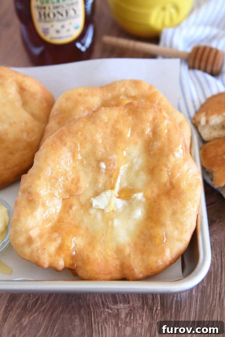 Several pieces of warm fry bread on baking tray with butter and honey.