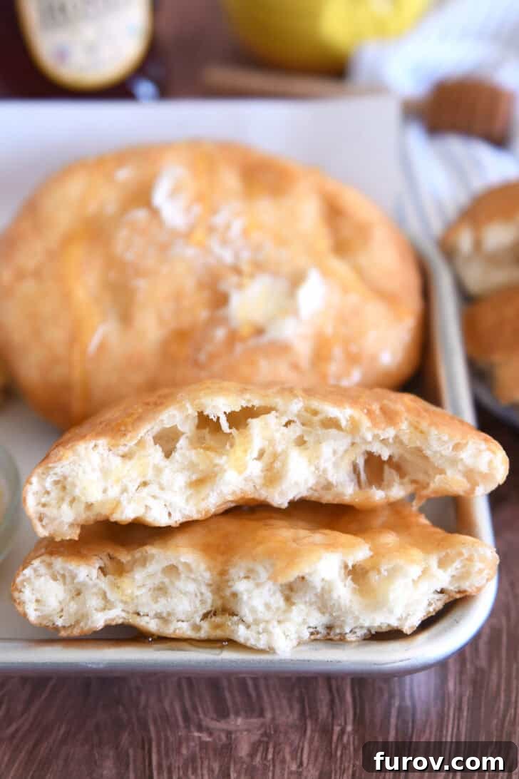 Piece of cooked fry bread cut in half on tray with honey.