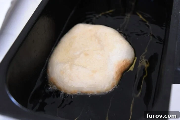 Piece of fry bread dough in electric oil fryer.