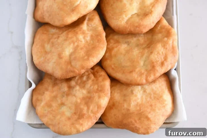Six pieces of cooked fry bread on paper towel lined baking sheet.