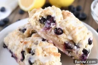 Two triangle-shaped baked lemon blueberry scones on white plate.