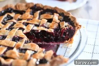 Triple berry pie in glass pie dish with one piece removed.