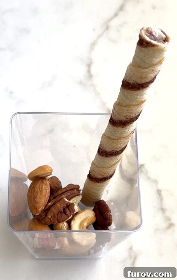 Square plastic cup with nuts and pirouline.