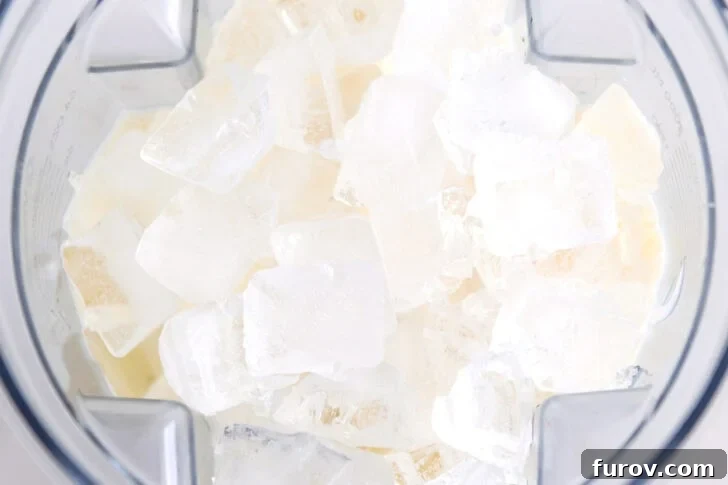Cubed ice in blender with pina colada ingredients.