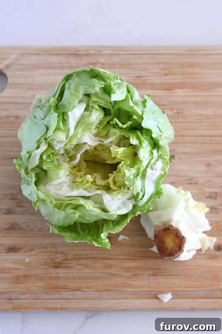 Loaded Wedge Salad with Bacon, Blue Cheese and Ranch Dressing 4 Wood cutting board with cored head of iceberg lettuce.