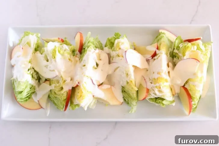 Loaded Wedge Salad with Bacon, Blue Cheese and Ranch Dressing 8 White platter with iceberg wedges, sliced apples, and blue cheese dressing.