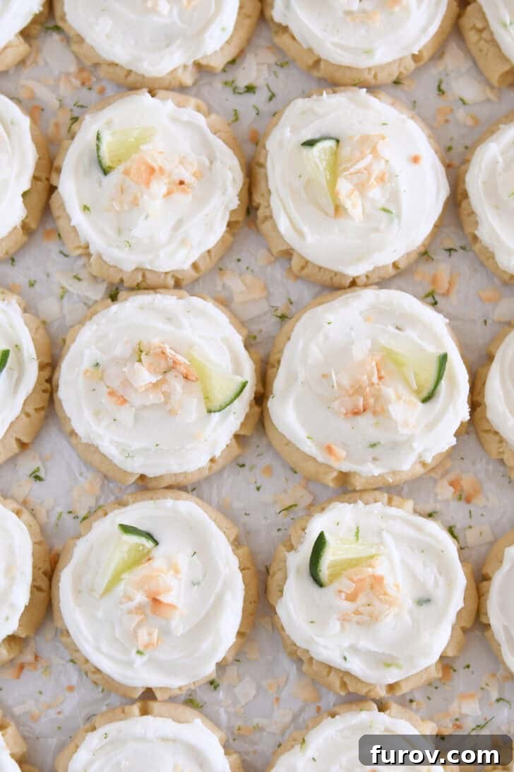 Copycat Swig Coconut Lime Sugar Cookies 9 Lots of frosted coconut lime sugar cookies topped with toasted coconut and a fresh lime wedge on white parchment paper.