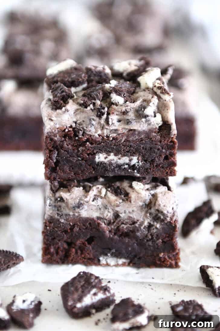 Two Oreo frosted brownies stacked on white parchment paper.