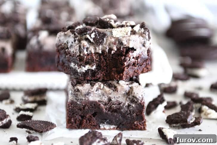 Two cookies and cream brownies stacked with bite taken out of top brownie.