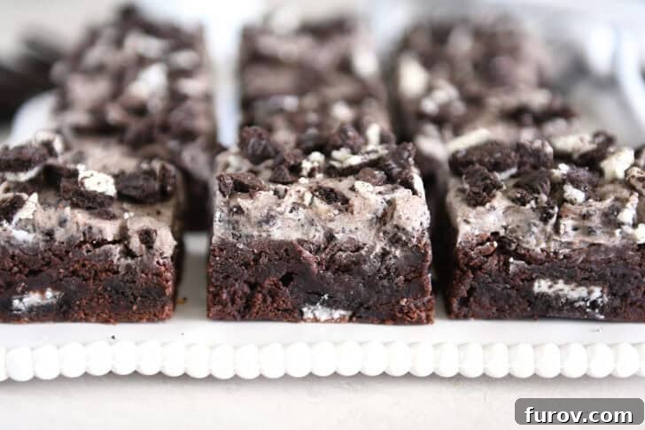 Three squares of Oreo frosted brownies on white tray.