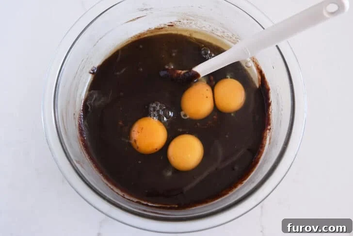 Glass bowl with melted chocolate batter and eggs.