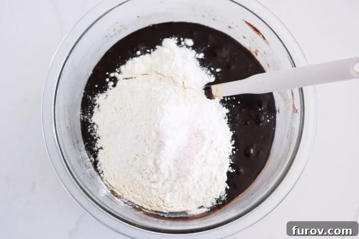 Glass bowl with melted chocolate batter, flour and salt.