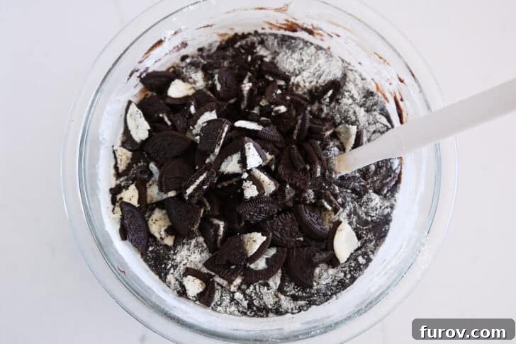 Glass bowl with brownie batter and chopped Oreos.