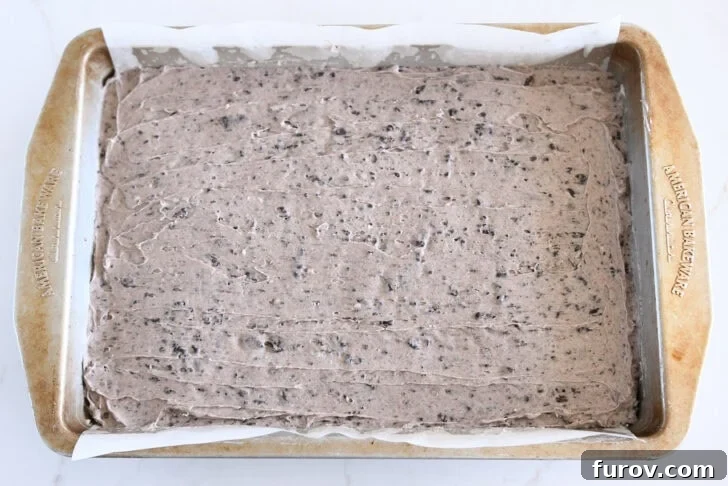Oreo frosting spread on top of baked pan of brownies.